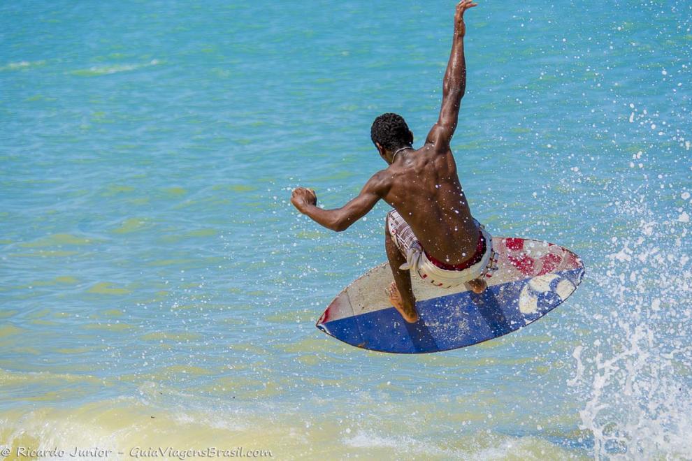 Imagem de um surfista fazendo manobras nas águas da Praia do Mutá.